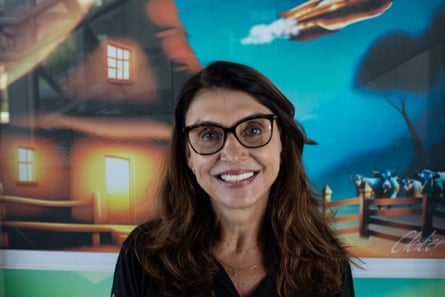 Varginha’s tourism secretary, Rosana Carvalho, stands in front of a mural smiling at the camera.