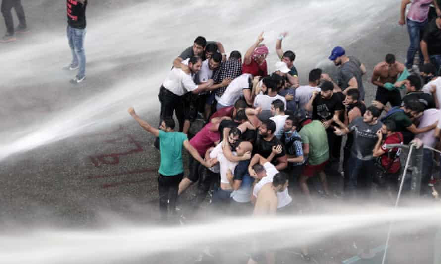 Lebanese activists are sprayed by riot police using water cannons during Sunday’s protest.