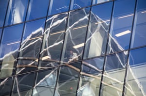 An office worker is seen through the reflection of the Gherkin building in Leadenhall, August 2020
