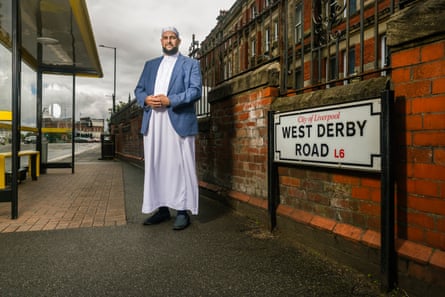 Imam Adam Kelwick. He is stood by a street sign for West Derby Road in Liverpool