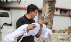 man holding child's body covered by shroud