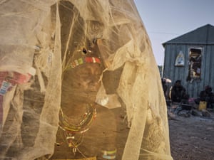 a woman looks out through gauze thrown over a shelter