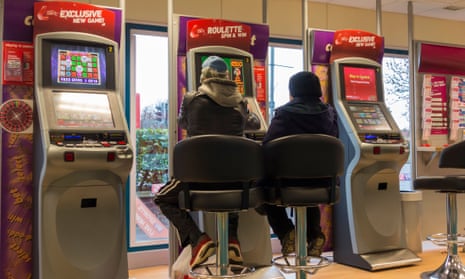 Man and woman at fixed odds gaming machines (FOBT fixed odds betting terminal) in Ladbrokes Betting shop. UKDR4788 Man and woman at fixed odds gaming machines (FOBT fixed odds betting terminal) in Ladbrokes Betting shop. UK