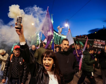A woman holds aloft a smoke flare as people carry flags