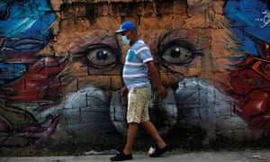 A resident walks with a face mask in front of a mural during a disinfection day in the Chorrillo neighborhood to combat the spread of the coronavirus, in Panama City, Panama, 30 June 2020.