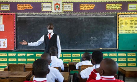 A teacher in Kampala welcomes back students on the day schools reopened in Uganda.