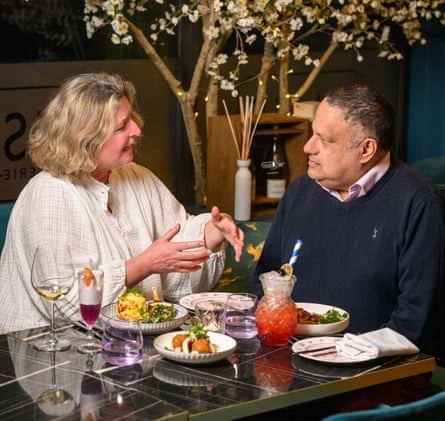 A woman and man facing each other across a restaurant table