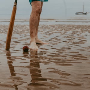 Close up of a cricket bat and ball on a sandbank off the north Norfolk coast; the boat, the Salford, is in the distance, on the horizon.