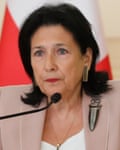 Salome Zourabichvili standing behind a microphone, with the Georgian flag in the background