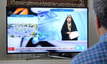 A man watches tv reporter in Tehran, Iran after Iranian official TV confirms 'massive explosions' in central Isfahan province