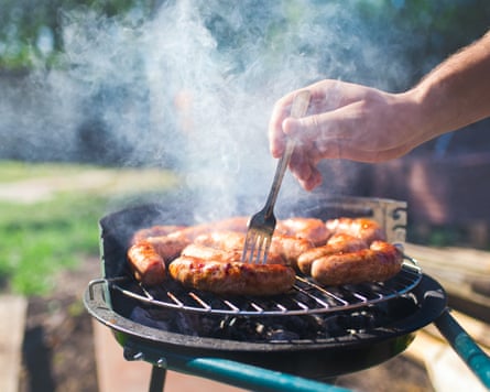 Sausages are fried on a barbecue.