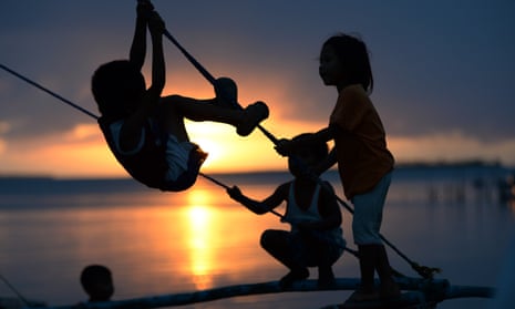 Children play on a wooden fishing boat as the sun sets in Guiuan town, central Philippines