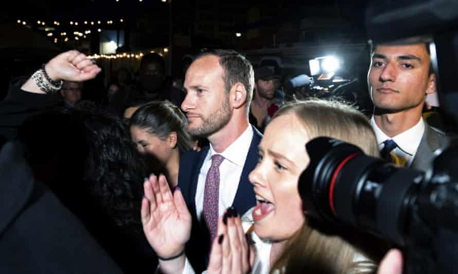 boudin looks serious while a woman next to him applauds