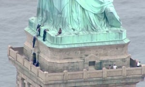 This still image taken from video Courtesy of PIX11 News in New York, shows police talking to a woman who has climbed to the base of the Statue of Liberty in New York. 1768.jpg?w=300&q=55&auto=format&usm=12&f