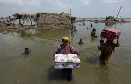 Women wade through floodwater carrying boxes