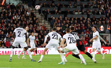 Evanilson leaps to head the ball while opposing players in white jerseys surround him