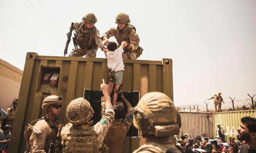 Western forces assist a child during an evacuation at Kabul airport on 20 August