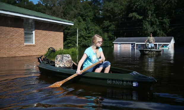 Alexis Ray paddles away from her mother’s flooded house as water that breached dams upstream continue to reach areas in the eastern part of the state on Thursday.
