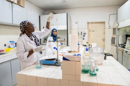 Two young African women in lab coats testing a sample of liquid in a laboratory