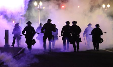 Policemen walk enveloped by teargas in Portland, Oregon.