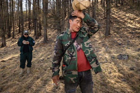 Ranger E Munkh-Erdene mops his head while examining a recent burn site
