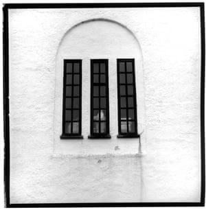 Three window frames embedded within a white arch on a wall