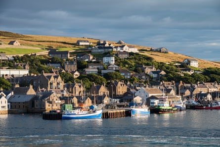 Boats docked by a small settlement with a hill behind