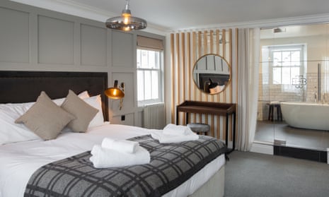 Bedroom, with a bathroom and bath behind a see-through glass wall, at the Black Bull, Sedbergh, Cumbria.