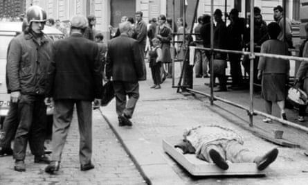 Citizens pass a body in the street.