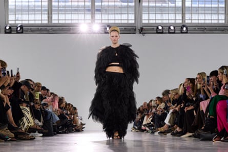 Model wears dramatic black two piece outfit.