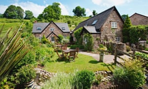 Stone farmhouse, with manicured gardens in front and hillside behind