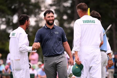 Jon Rahm of Spain shakes hands with Cameron Young’s caddie Paul Tesori on the 18th green.