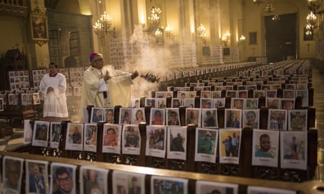 The Archbishop of Lima, Carlos Castillo, swings a censer over several of the thousands of portraits of Peru’s Covid-19 victims during mass on Sunday.
