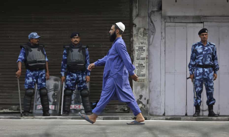 A Muslim man walks past Indian paramilitary soldiers after offering prayer during Eid al-Adha in Jammu
