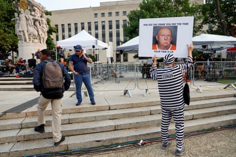 A man holds a placard before the eventual arrival of former U.S. President Donald Trump at US District Court in Washington.
