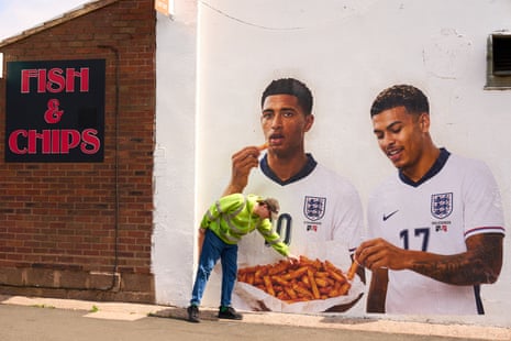 Artist Dion Kitson with the mural he’s painted at the Classic Fryer chip shop in Quinton featuring local-born heroes Jude Bellingham (Stourbridge) and Morgan Rogers (Halesowen).