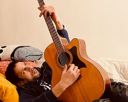 Joe Black lying on a bed, playing the guitar