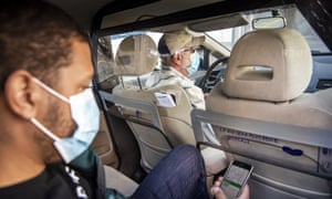 An Uber driver and customer, both in face masks, take a ride in Switzerland.