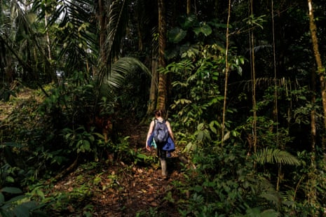 Mandie Quark usando galochas e mochila caminha pela floresta amazônica no Equador.