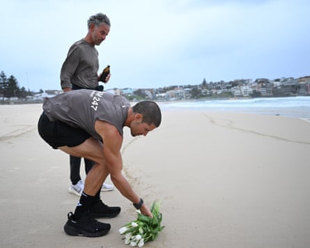 William Goodge is joined by his father as he places a bunch of lilies at the shoreline of Bondi beach in memory of his mother