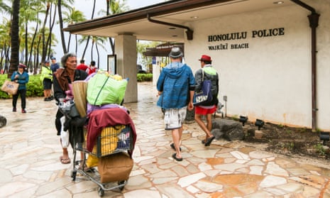 A homeless man pushes a shopping cart past the Waikiki station for the Honolulu police department.