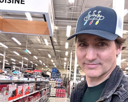 A man, wearing a baseball cap in a store, taking a selfie