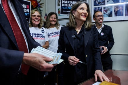 A woman smiles as she holds a pen.