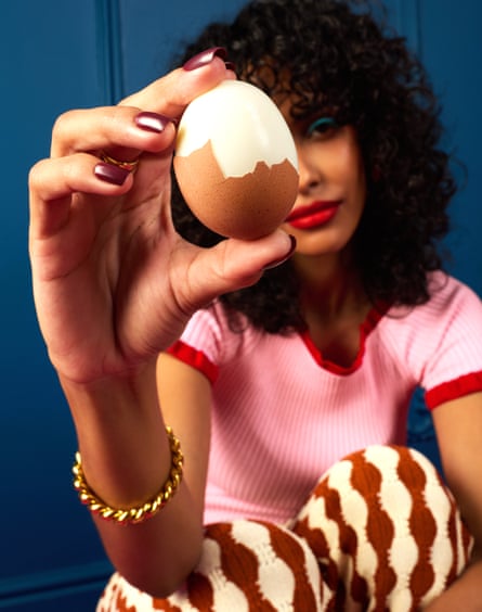 Woman holding a half-peeled egg in front of her face