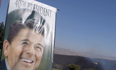 A banner hangs at the entrance to the Ronald Reagan presidential library as a helicopter flies over nearby burned hills on 30 October 2019.