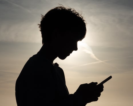 Teenage boy looks at his smartphone.