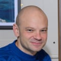 A portait of a smiling bald man wearing a bright blue patterned jumper