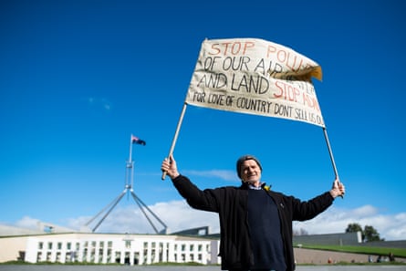 A protestor holding signage during the anti-Adani rally outside Parliament House in Canberra on 5 May.