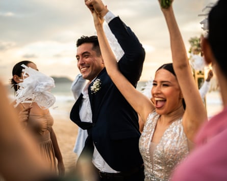 A man and a woman at a wedding ceremony, holding their hands above their heads
