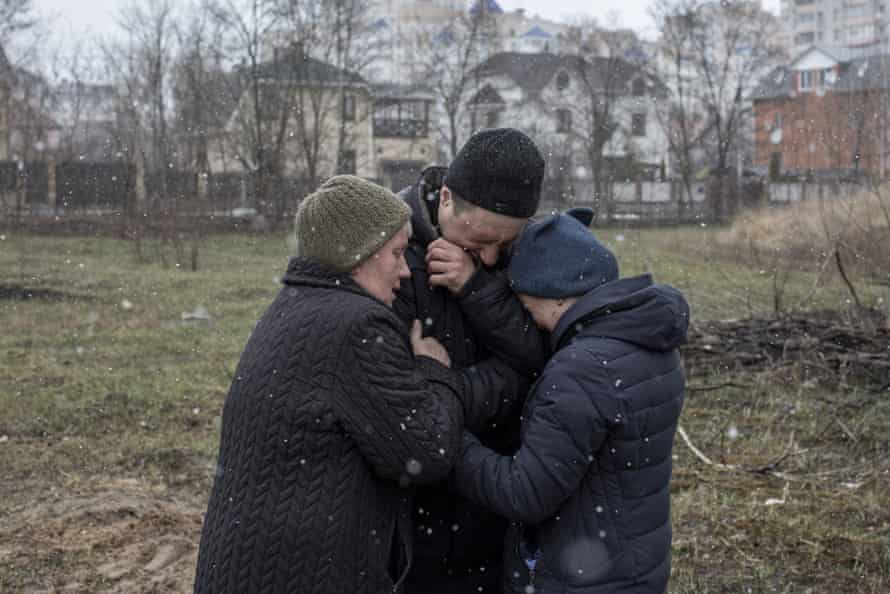A family grieve for a missing relative in front of a mass grave in the town of Bucha